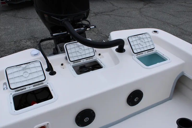 Slide: The Image of 2025 Sundance B22CCR boat with open storage compartments and motor, showcasing functionality. - 16