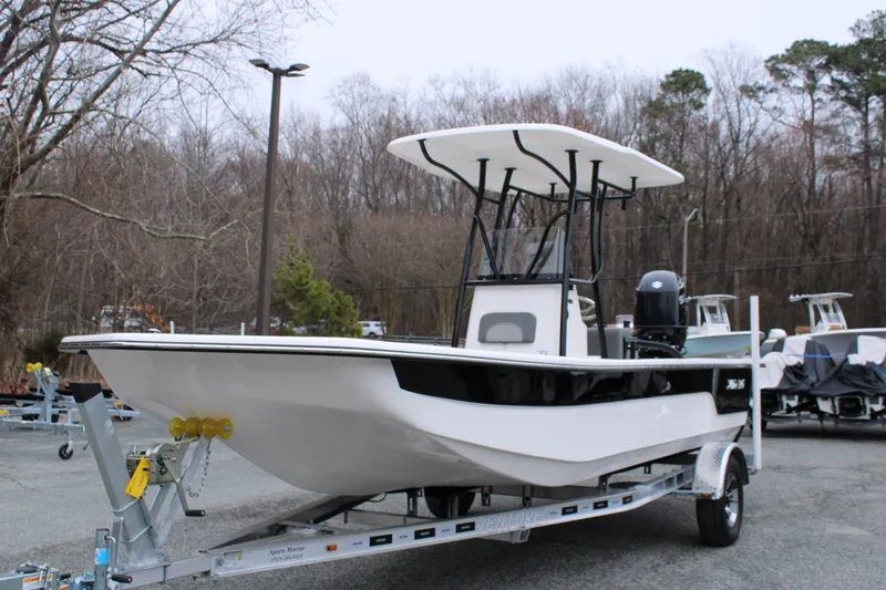 Slide: The Image of 2025 Sundance B22CCR boat on trailer, parked outdoors, surrounded by trees. - 2