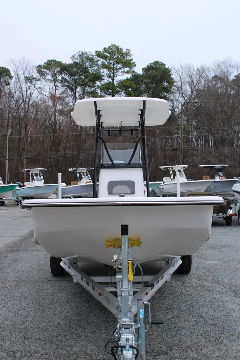 Slide: The Image of 2025 Sundance B22CCR boat on trailer, parked outdoors, surrounded by trees and other boats. - 6