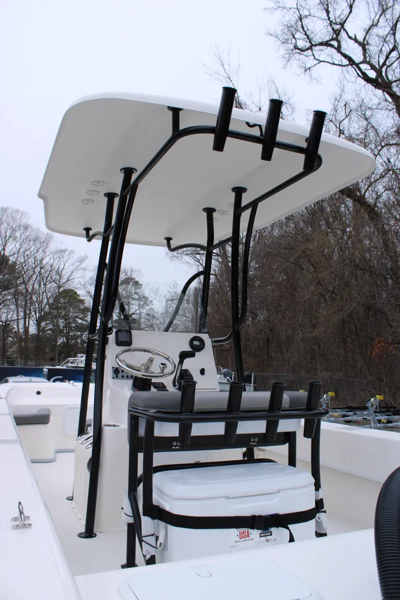 Slide: The Image of 2025 Sundance B22CCR boat with T-top and seating, set against a wooded backdrop. - 7