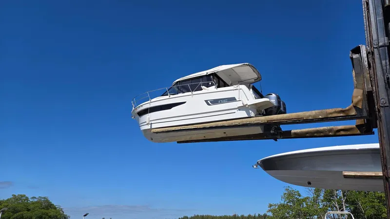 Slide: The Image of 2019 Jeanneau NC895 boat lifted by forklift against clear blue sky. - 3
