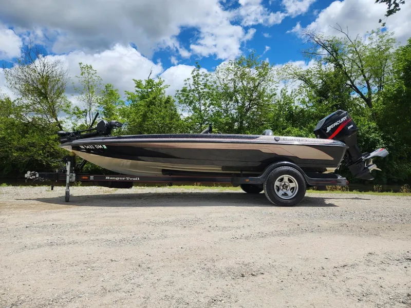 Slide: The Image of 2002 Ranger 185VS boat on trailer, parked outdoors with trees and cloudy sky background. - 1