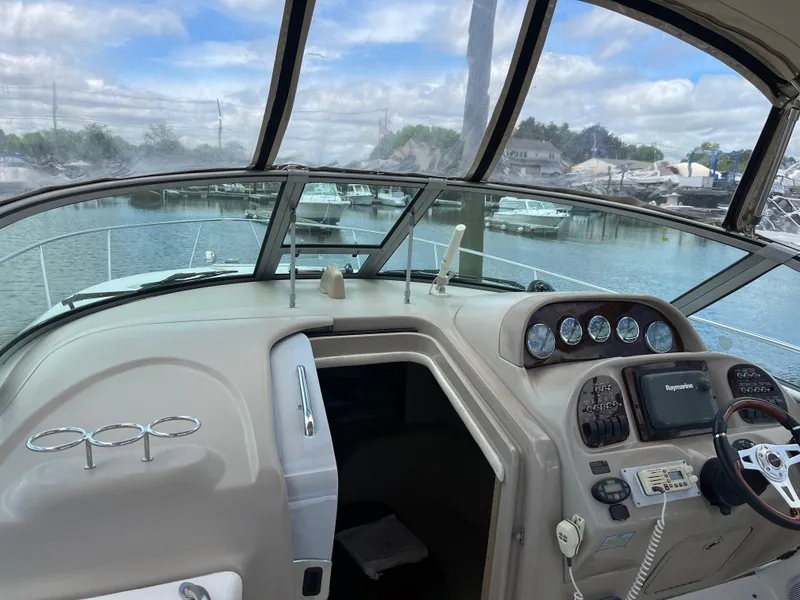 Slide: The Image of 2005 Sea Ray 300 Sundancer helm with gauges, steering wheel, and marina view. - 14