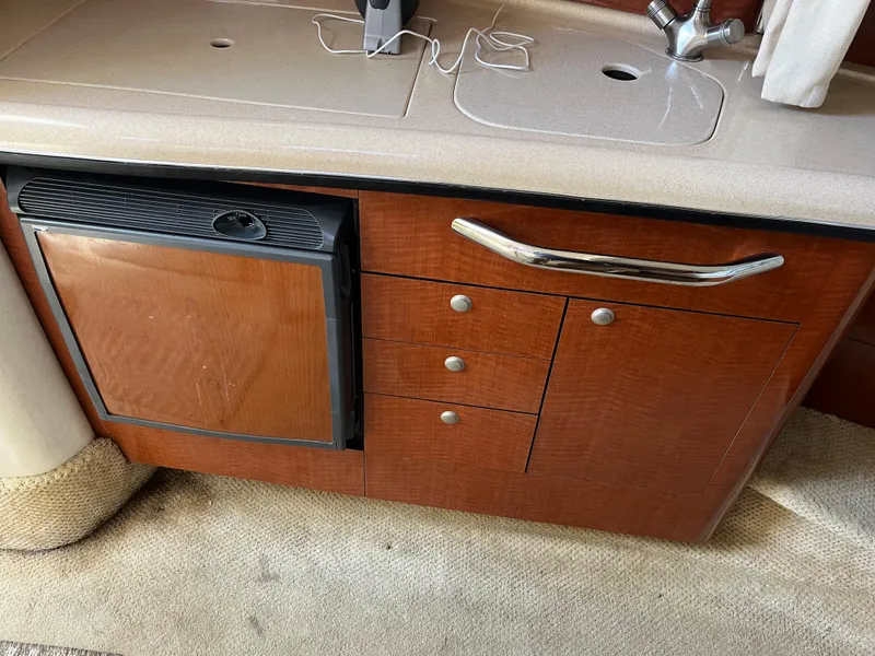 Slide: The Image of Interior of 2005 Sea Ray 300 Sundancer with wooden cabinetry and mini fridge. - 16