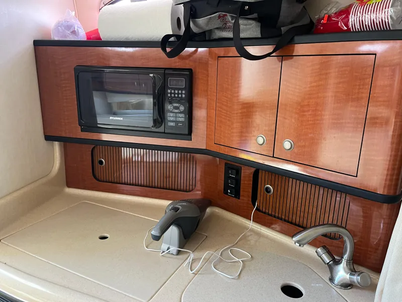 Slide: The Image of 2005 Sea Ray 300 Sundancer galley with microwave, sink, and storage cabinets. - 17