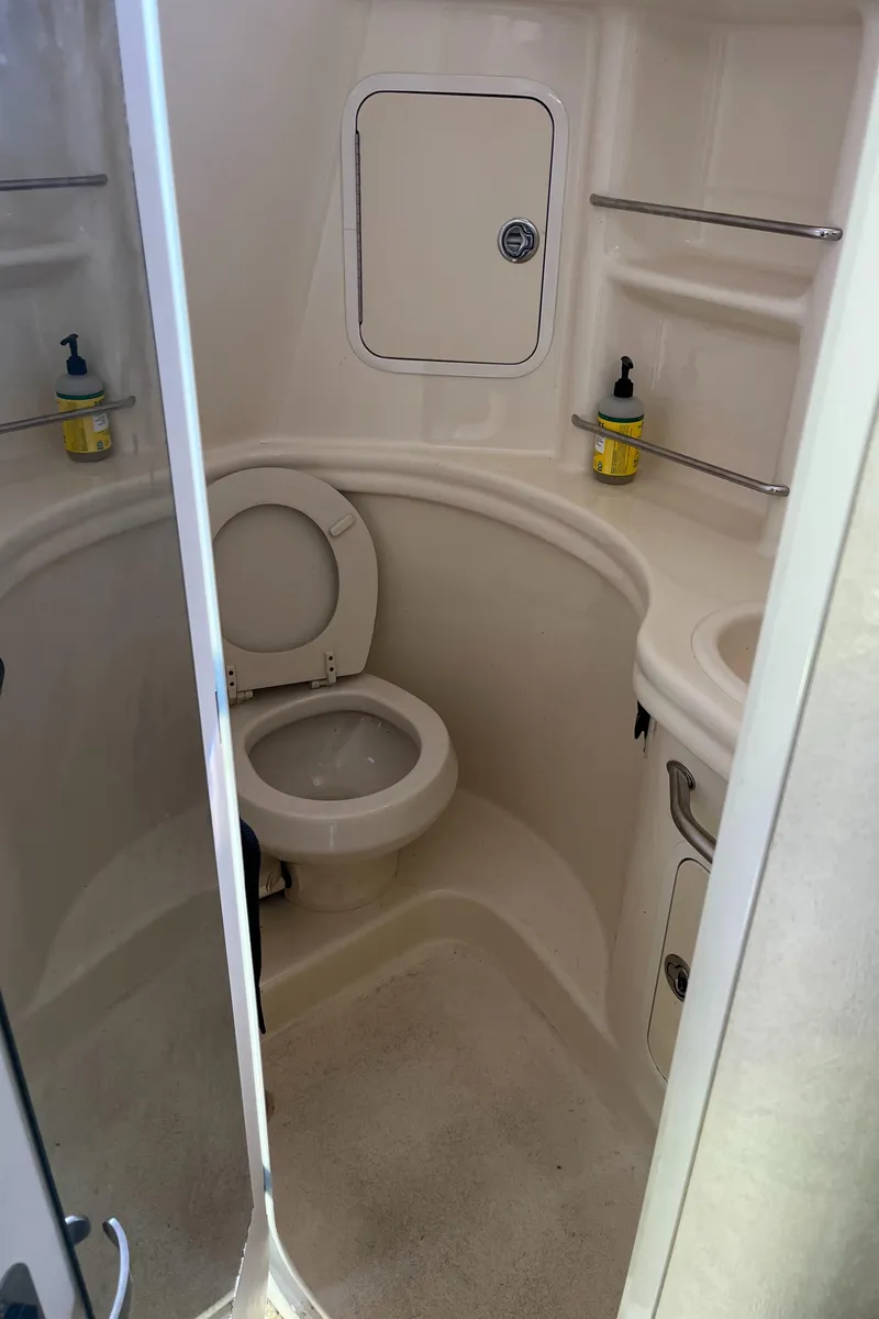 Slide: The Image of 2005 Sea Ray 300 Sundancer bathroom with toilet and storage shelves. - 25