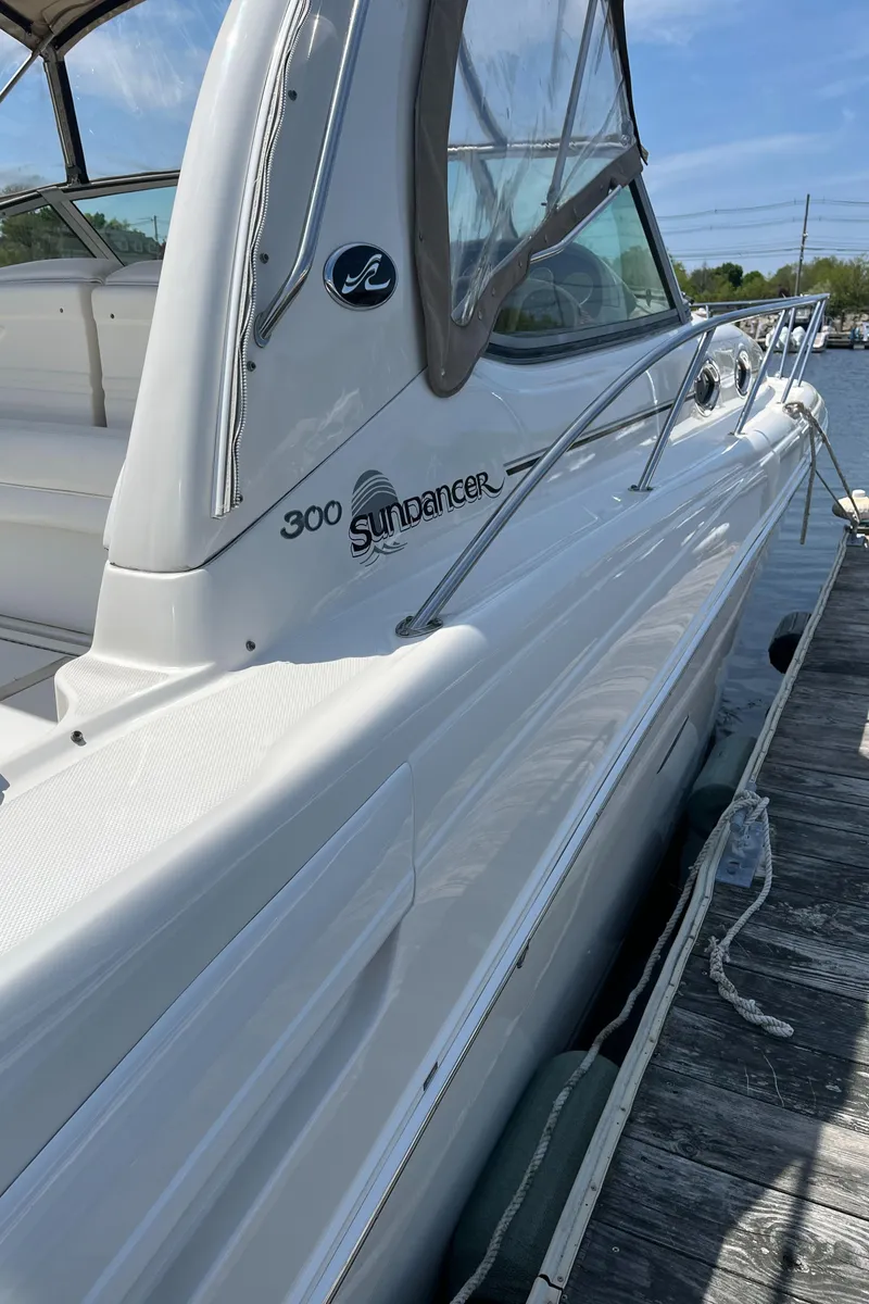 Slide: The Image of 2005 Sea Ray 300 Sundancer boat docked, showcasing sleek white design and spacious deck. - 27