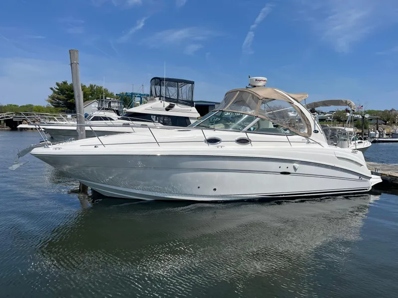 Slide: The Image of 2005 Sea Ray 300 Sundancer boat docked in a marina under a clear blue sky. - 5