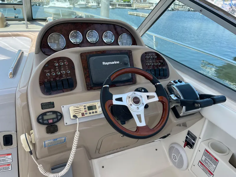 Slide: The Image of 2005 Sea Ray 300 Sundancer helm with Raymarine display and wood-accented steering wheel. - 8