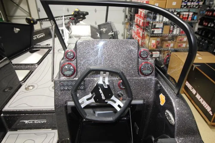 Slide: The Image of 2025 Yar-Craft 210TFX SP boat dashboard with steering wheel and gauges in a garage setting. - 13