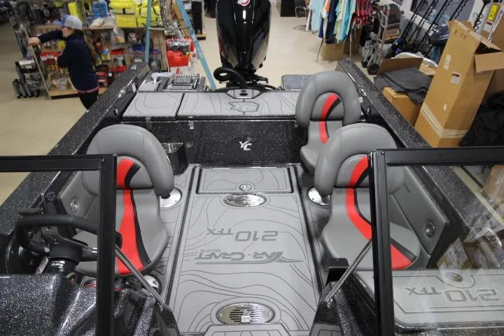 Slide: The Image of 2025 Yar-Craft 210TFX SP boat interior with gray and red seating in a showroom. - 15