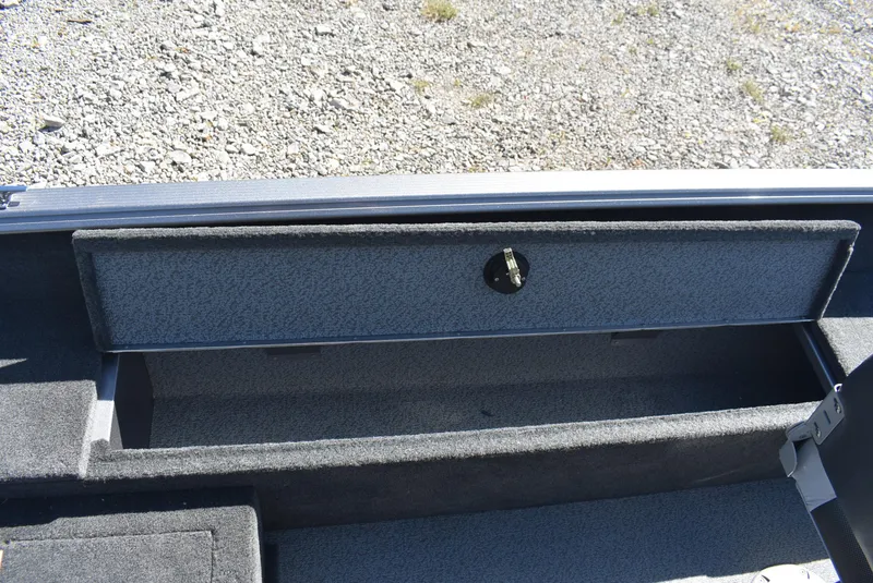 Slide: The Image of 2014 Lund 1675 Impact SS boat storage compartment with open lid on gravel background. - 11