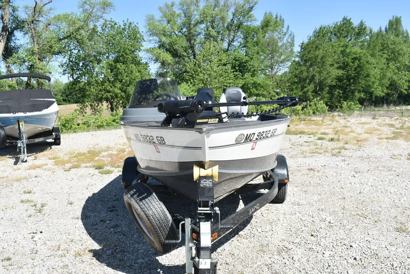 Slide: The Image of 2014 Lund 1675 Impact SS boat on trailer, parked outdoors with trees in background. - 2