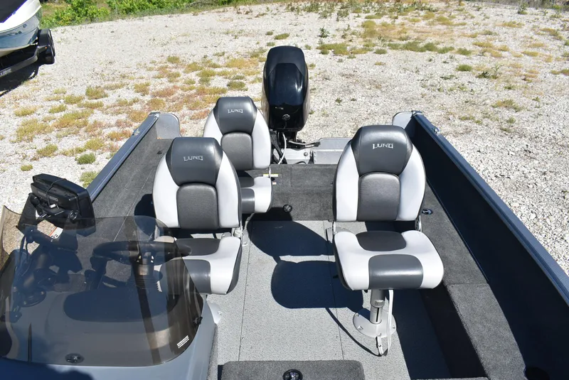 Slide: The Image of 2014 Lund 1675 Impact SS boat with four seats and motor, parked on gravel. - 6