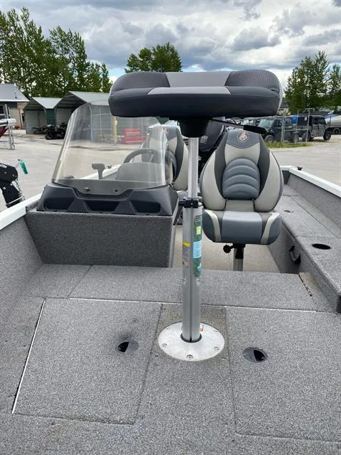 Slide: The Image of 2022 Alumacraft Escape 145 CS boat interior with seating and console, parked outdoors. - 3