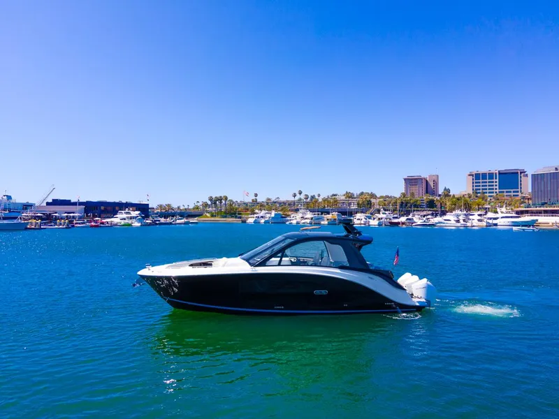 Slide: The Image of 2022 Sea Ray Sundancer 370 OB cruising in a sunny marina with cityscape background. - 10