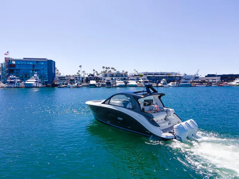 Slide: The Image of 2022 Sea Ray Sundancer 370 OB cruising in a marina with yachts and buildings. - 11