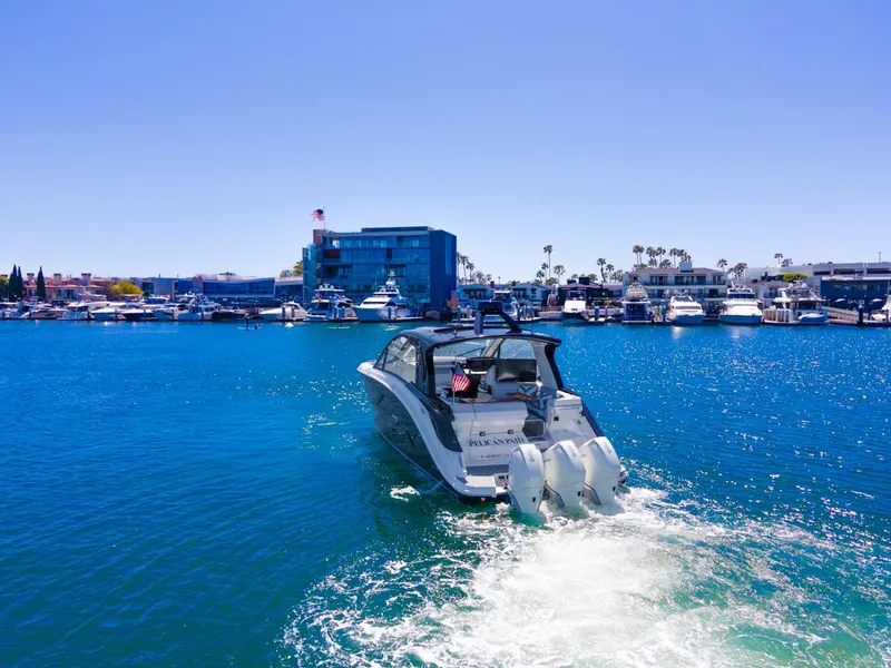 Slide: The Image of 2022 Sea Ray Sundancer 370 OB cruising in a vibrant marina under clear blue skies. - 13