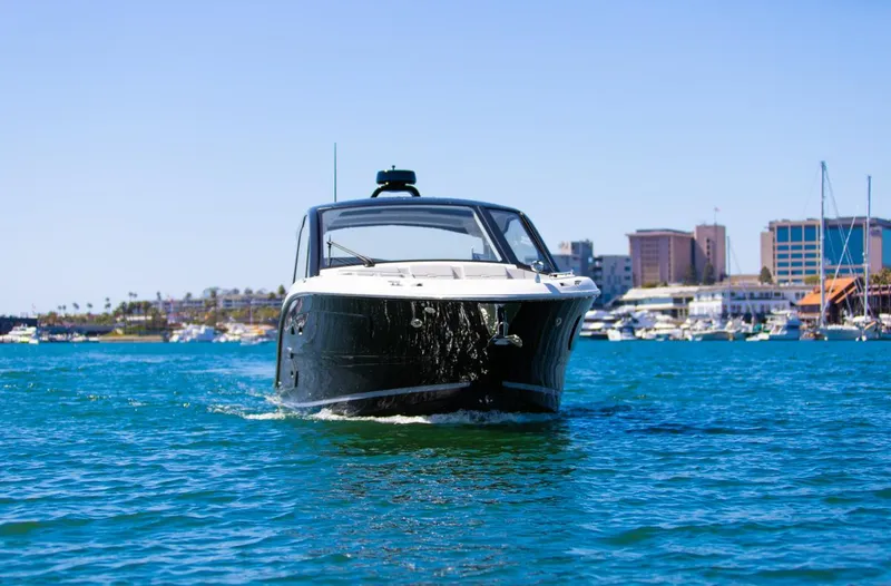 Slide: The Image of 2022 Sea Ray Sundancer 370 OB cruising on blue water near a cityscape. - 28