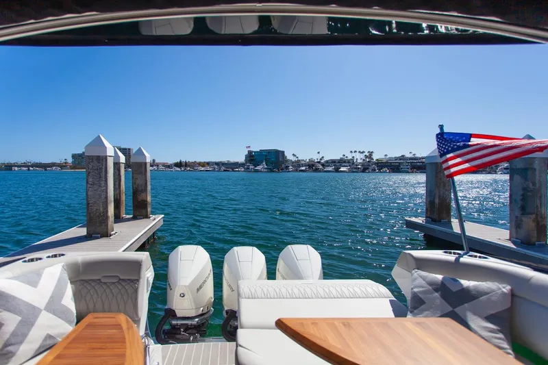 Slide: The Image of 2022 Sea Ray Sundancer 370 OB at dock, featuring triple outboard engines and American flag. - 47