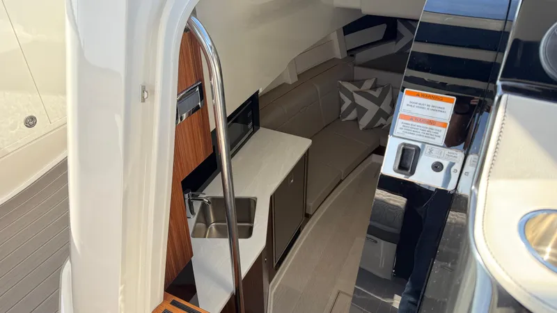 Slide: The Image of Interior of 2022 Sea Ray Sundancer 370 OB, featuring a compact kitchenette and seating area. - 49