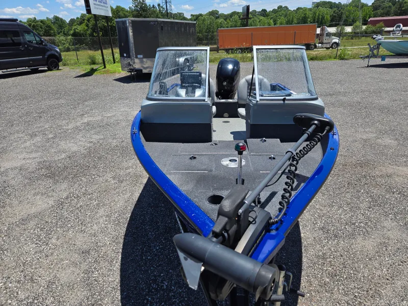 Slide: The Image of 2018 Tracker Pro Guide V-16 WT boat with blue trim, parked outdoors. - 2
