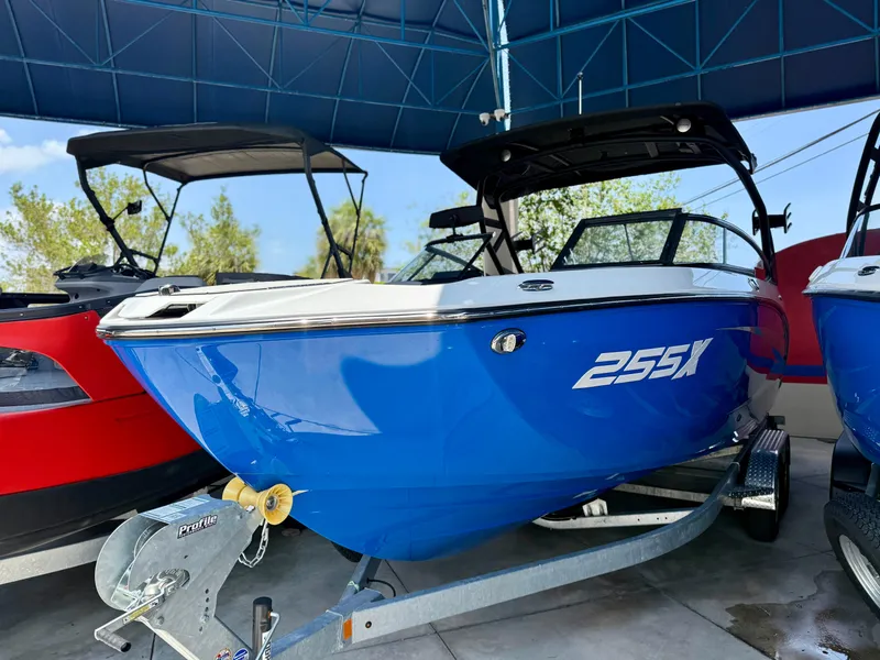The Image of 2025 Yamaha Boats 255XD in blue, displayed on a trailer under a canopy. - 0