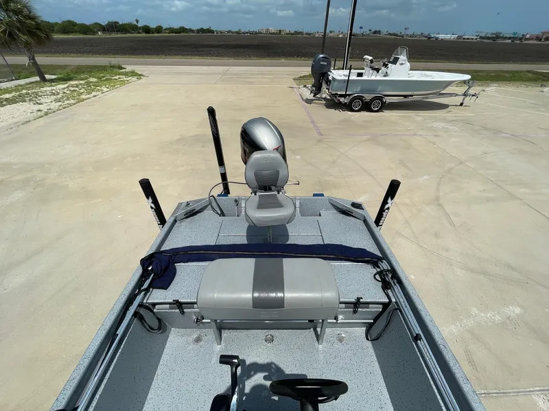 Slide: The Image of 2019 Xpress XP20CC boat with seating and motor, parked on concrete near another boat. - 10