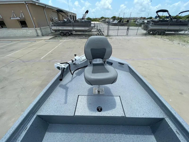 Slide: The Image of 2019 Xpress XP20CC boat with gray seating and trolling motor, parked outdoors. - 24