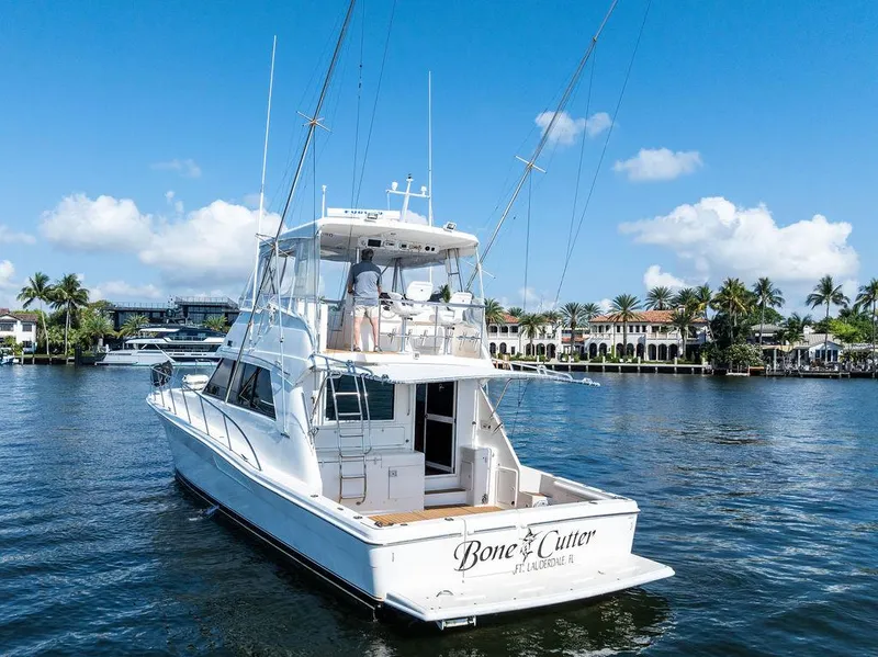 Slide: The Image of Riviera 48 yacht from 2001 on a sunny waterfront, featuring a spacious deck. - 10