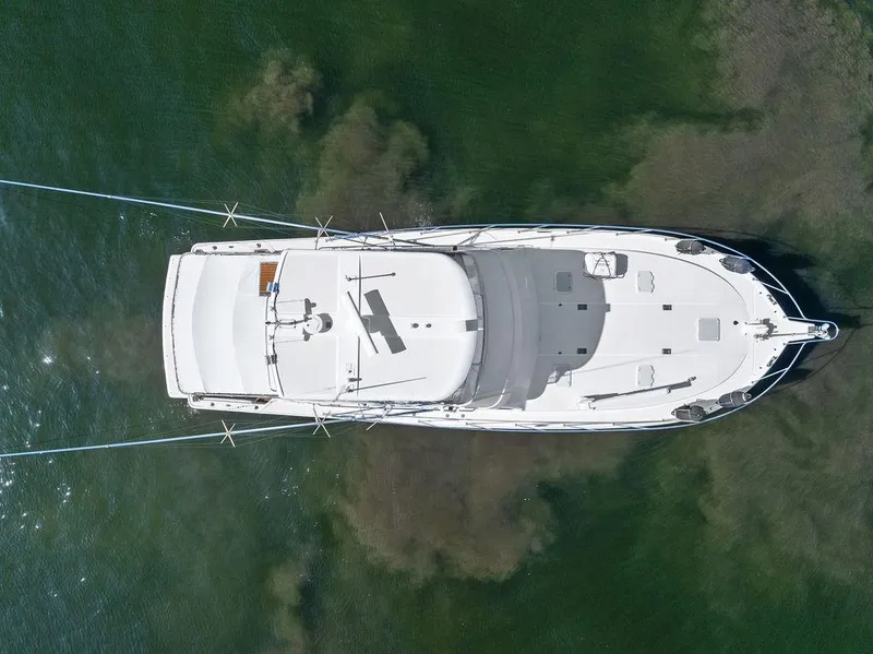 Slide: The Image of 2001 Riviera 48 yacht cruising on a sunny day, surrounded by waterfront homes. - 12