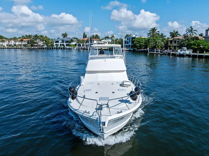 Slide: The Image of 2001 Riviera 48 yacht cruising on a sunny day in a scenic harbor. - 13