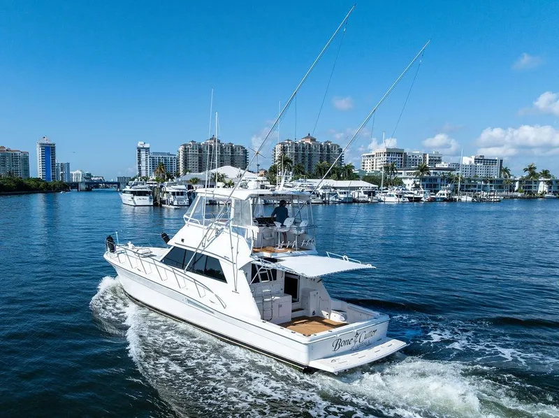 Slide: The Image of 2001 Riviera 48 yacht cruising on a sunny day, surrounded by calm waters and blue skies. - 15