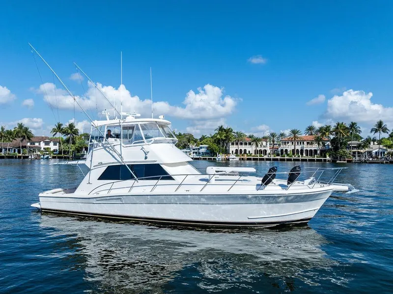 Slide: The Image of 2001 Riviera 48 yacht cruising on a sunny day, surrounded by waterfront homes. - 2