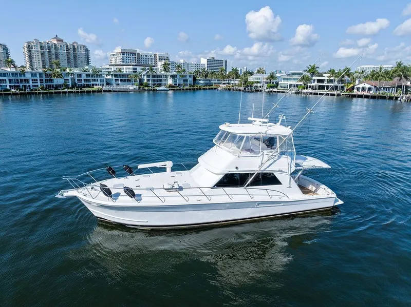 Slide: The Image of 2001 Riviera 48 yacht on calm water with waterfront buildings in the background. - 4