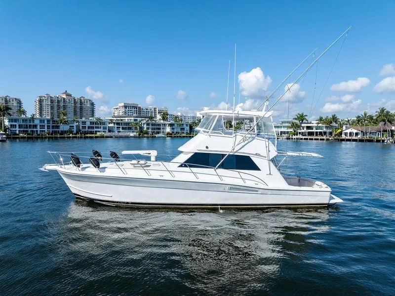 Slide: The Image of 2001 Riviera 48 yacht on calm water with cityscape background. - 5