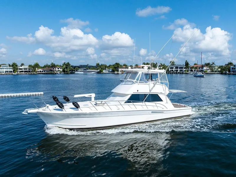 Slide: The Image of 2001 Riviera 48 yacht cruising in a marina with cityscape and palm trees. - 16