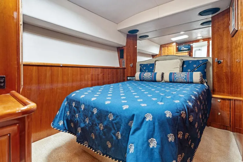 Slide: The Image of Luxurious 2001 Riviera 48 yacht cabin with wooden interior and blue bedding. - 48