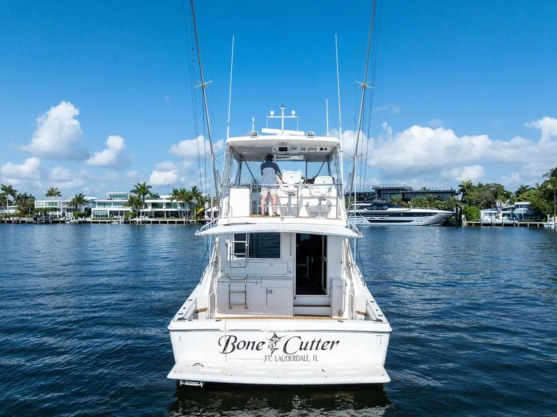 Slide: The Image of 2001 Riviera 48 yacht cruising on a sunny day near waterfront homes. - 9