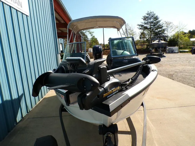 Slide: The Image of 2017 Ranger VS1780 boat with trolling motor, parked outdoors near a blue building. - 14
