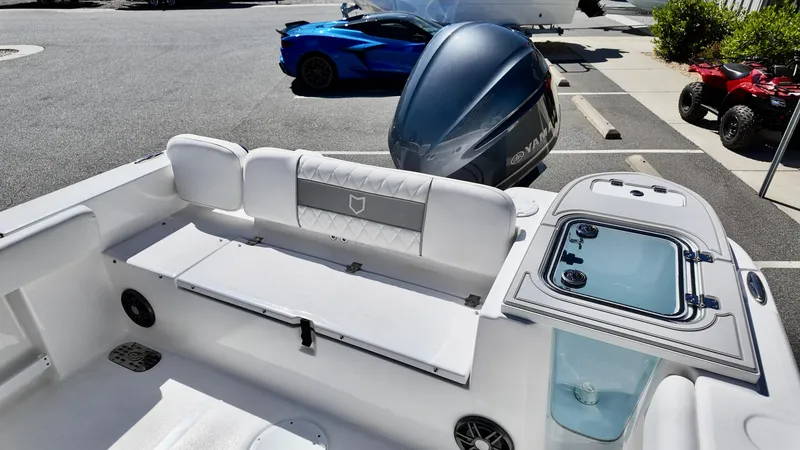 Slide: The Image of 2025 Sea Fox 248 Commander boat interior with seating and storage, parked near vehicles. - 18