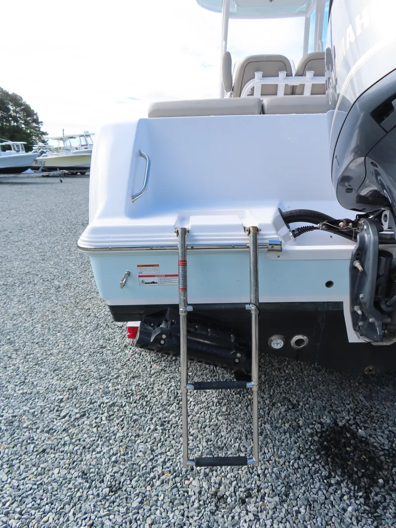 Slide: The Image of 2023 Sportsman Heritage 231 Center Console boat with rear ladder on gravel surface. - 6