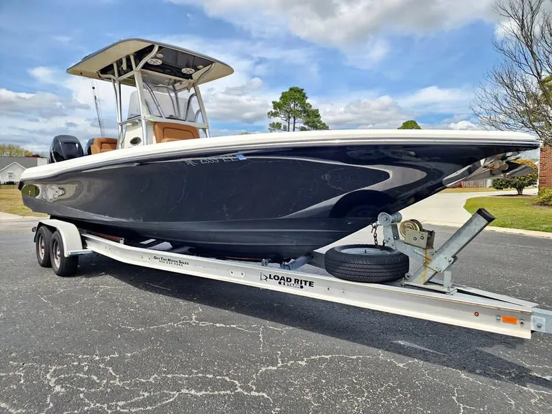 Slide: The Image of 2010 Blackwood 270 boat on trailer, parked outdoors under a cloudy sky. - 0