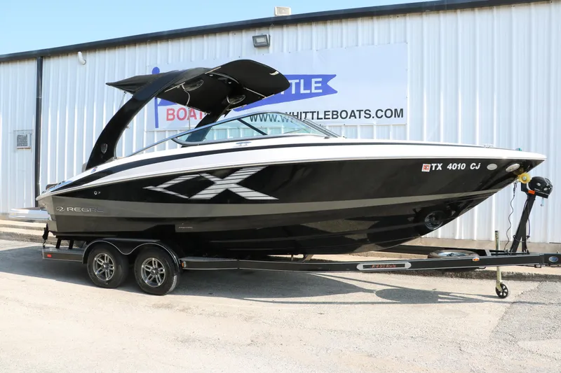 Slide: The Image of 2014 Regal 2500 RX Bowrider boat on trailer, black and white design, parked outside a building. - 1