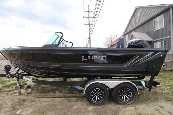 Slide: The Image of 2025 Lund 2075 Tyee boat on trailer, parked outdoors near houses. - 0