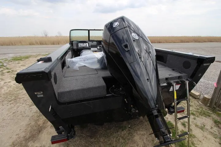 Slide: The Image of 2025 Lund 2075 Tyee boat with powerful outboard motor, parked on sandy terrain. - 2