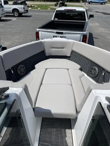 Slide: The Image of 2023 Four Winns H4 boat interior with gray seating and speakers, parked near a pickup truck. - 7
