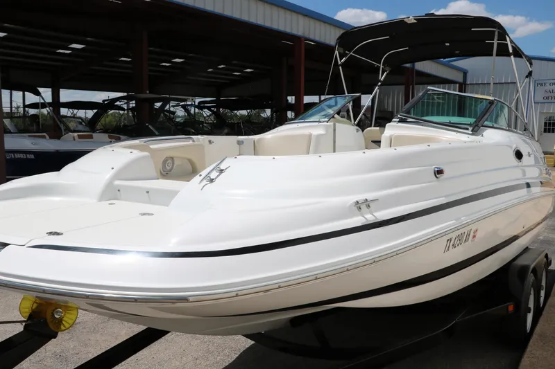 Slide: The Image of 2000 Chris-Craft 232 boat on trailer, white exterior, parked outdoors under blue sky. - 10