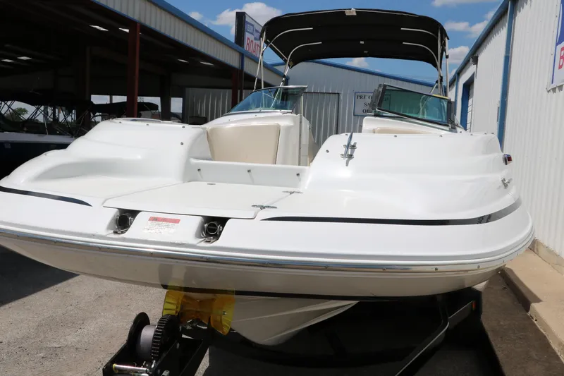 Slide: The Image of 2000 Chris-Craft 232 boat with canopy, docked in a marina under a clear blue sky. - 11