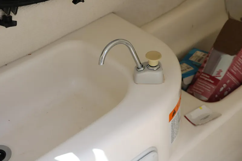 Slide: The Image of 2000 Chris-Craft 232 boat sink with faucet and storage area. - 32